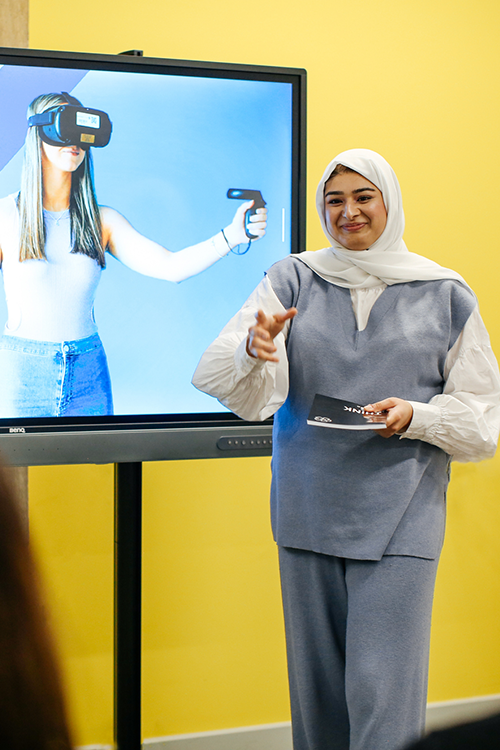 Teacher speaking to student while presenting to class
